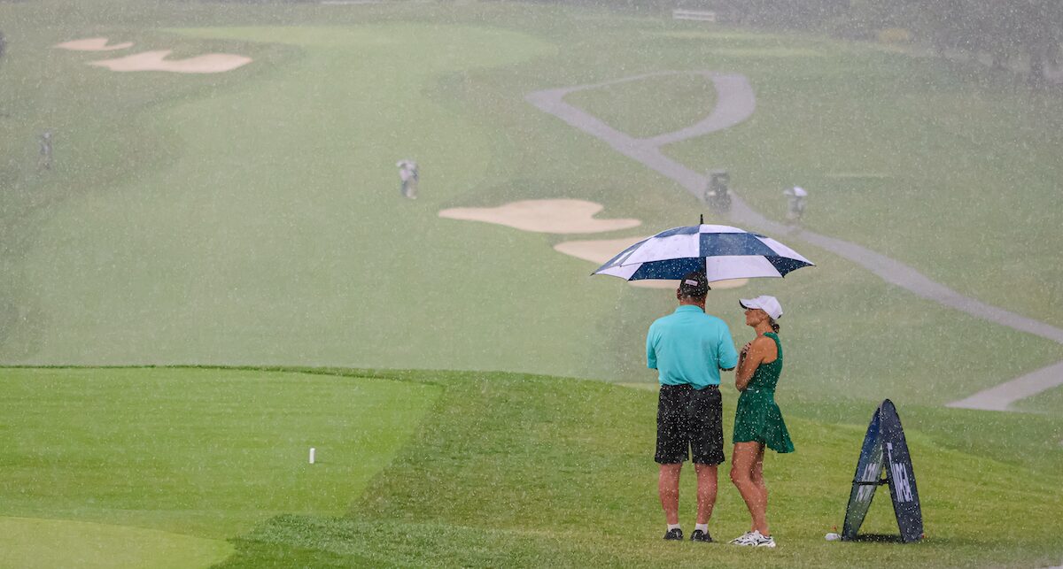 Spectators stand under umbrella at second round of 2025 WPGA Open Championship at Sewickley Heights Golf Club